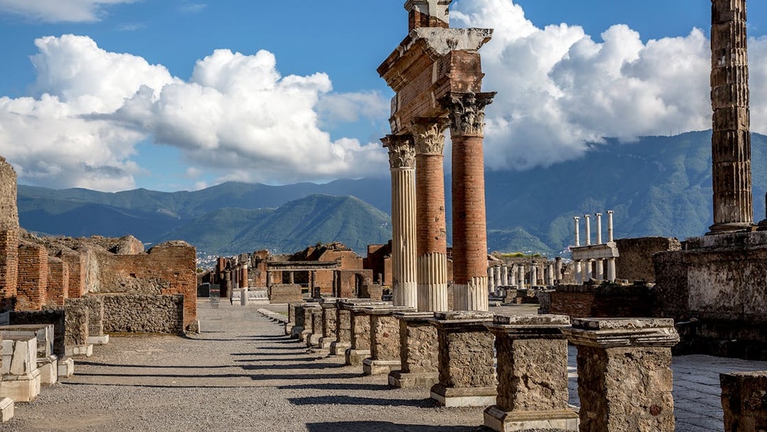 Guided tour group at Pompeii ruins with Mt. Vesuvius in background, near Naples.