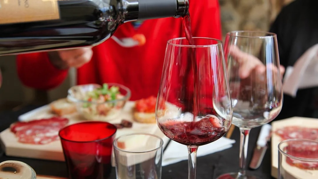 Pouring red wine at a Tuscan meal with charcuterie in Rome tour.