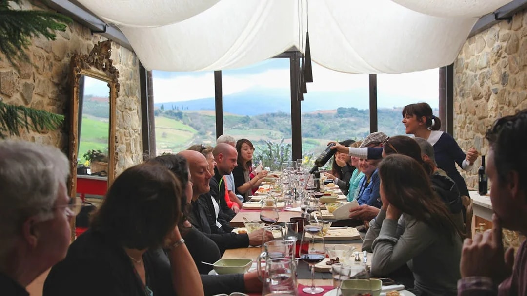 Group dining in a Tuscan restaurant with countryside views on a Rome day trip.