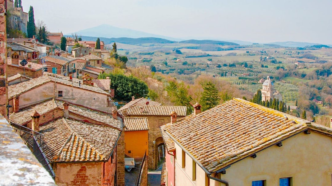 Tuscany countryside view with rustic rooftops and distant rolling hills.