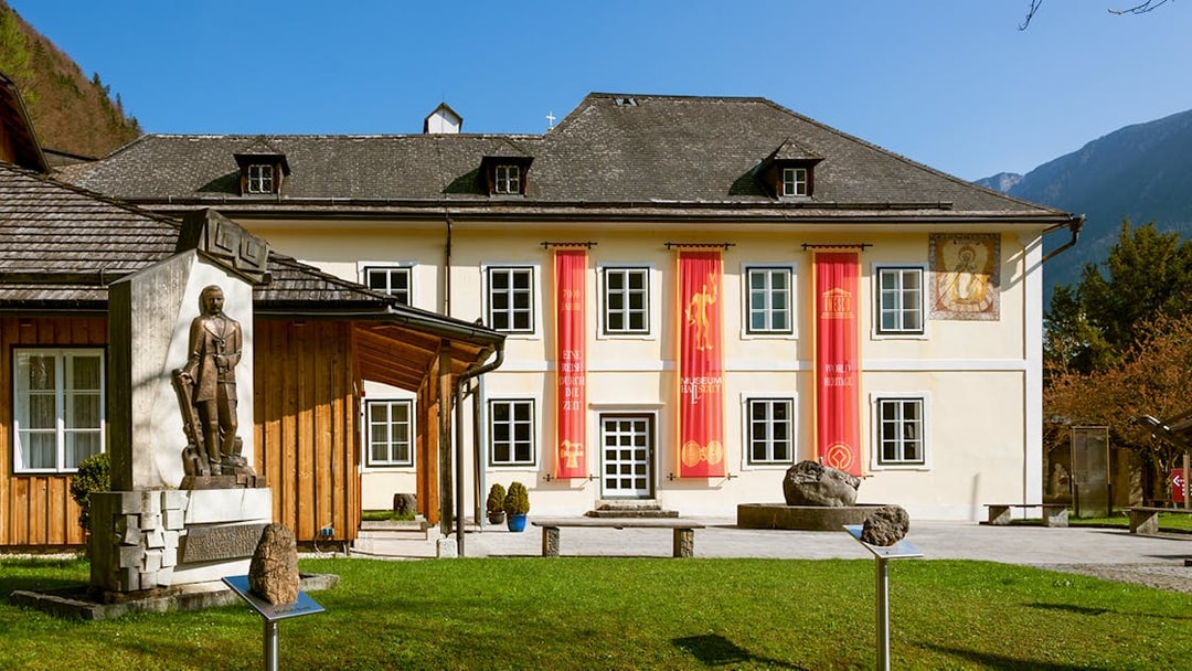 Hallstatt Museum exterior with red banners and historical statue in Austria.
