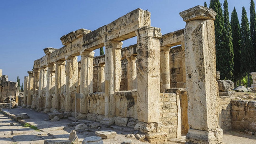 Ancient ruins of Hierapolis in Pamukkale, Turkey, with stone columns and clear sky.