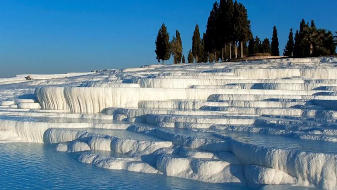 Pamukkale travertine terraces with clear blue pools in Turkey.