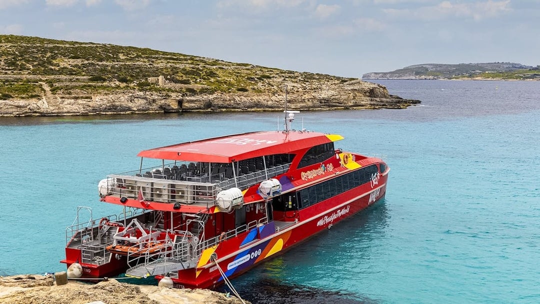 Cruise ship docked at Blue Lagoon, Malta with clear turquoise water.