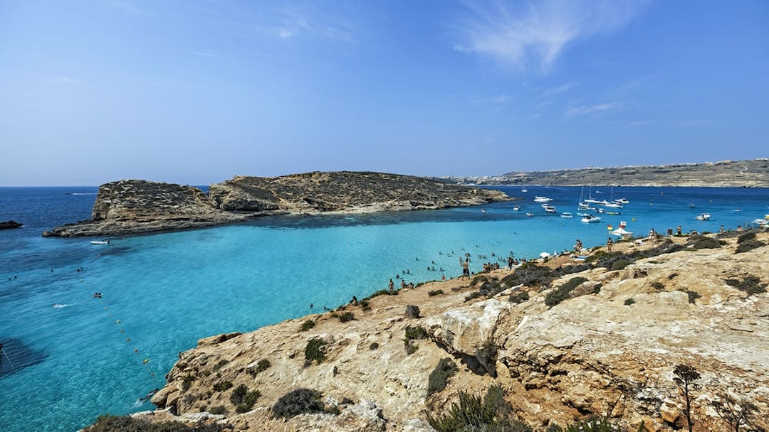 Blue Lagoon in Malta with clear turquoise water, rocky coastline, and anchored boats.
