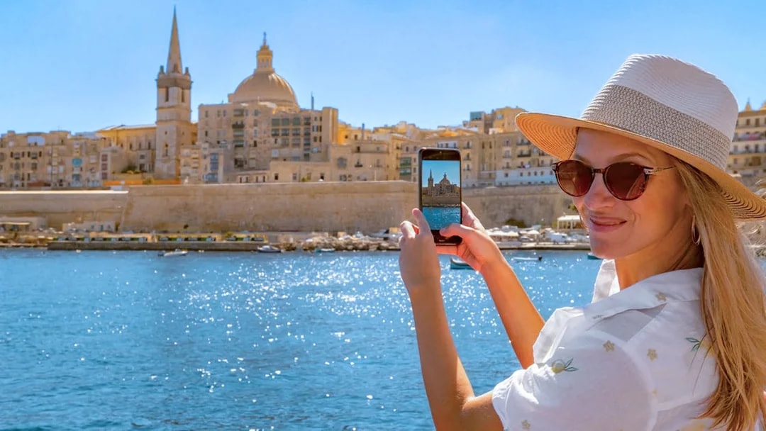 Woman photographing Valletta skyline from a boat on the Sliema Harbour Cruise.