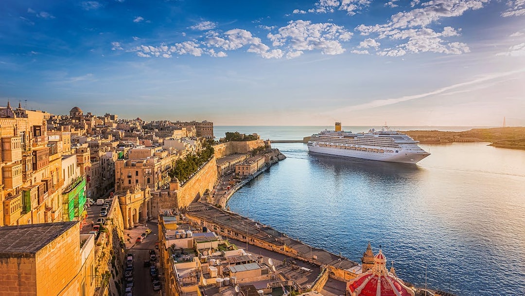 Cruise ship in Valletta harbor with historic cityscape, viewed from Sliema.