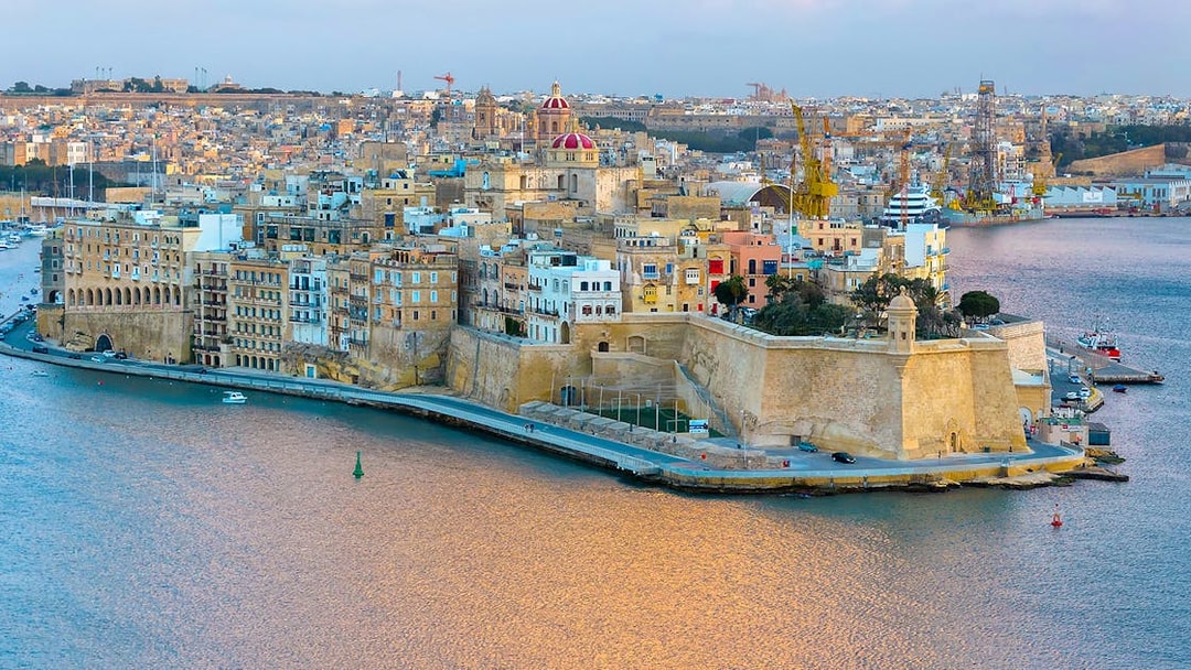 Valletta skyline and harbor view from Sliema, featuring historic buildings and waterfront.