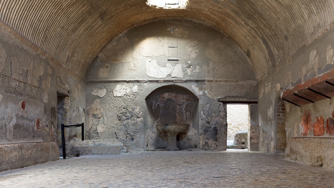 Central Baths interior at Herculaneum with vaulted ceiling and ancient stone basin.