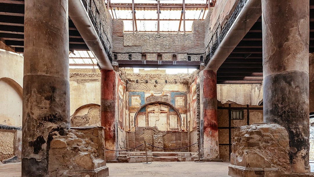 Interior of the College of the Augustales in Herculaneum with ancient frescoes and columns.