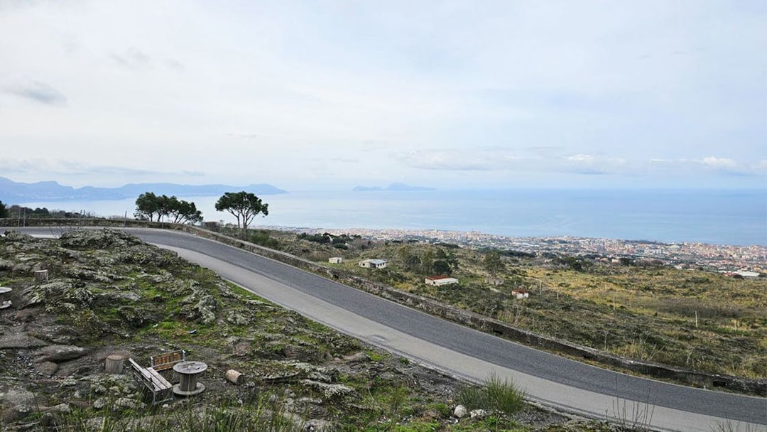 Winding road on Mount Vesuvius with view of Sorrento coastline and sea.