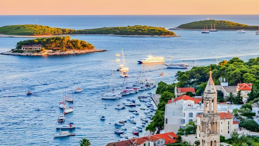 Boats sailing near Hvar Island with a view of the Adriatic Sea and coastal buildings.