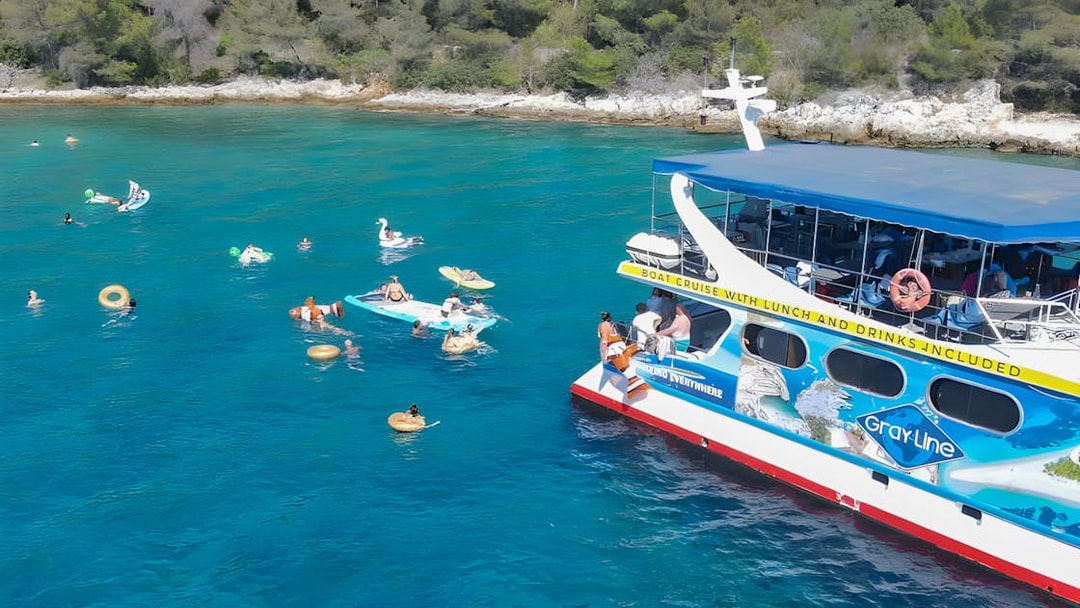 Tourists swimming near a cruise boat in Split, Croatia, with inflatable floats and nearby islands.