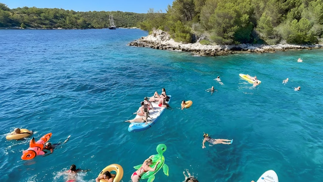 People enjoying a swim and paddleboarding near Hvar during a Split islands cruise.