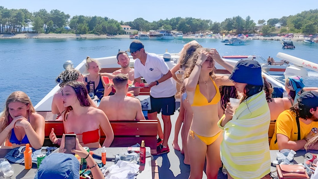 Group enjoying a boat cruise near Split, Croatia, with drinks and watermelon.