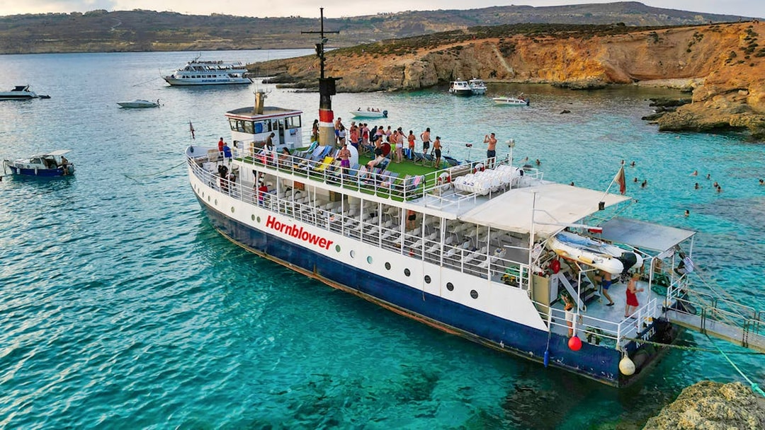 Cruise ship at Blue Lagoon with tourists enjoying the view and swimming in clear waters.