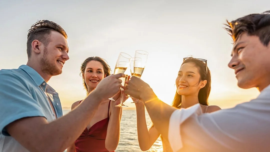 Friends toasting with drinks on a sunset cruise.