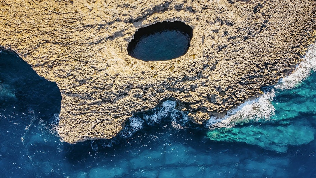 Aerial view of Ahrax fallen cave and Coral Lagoon, Malta with surrounding sea.