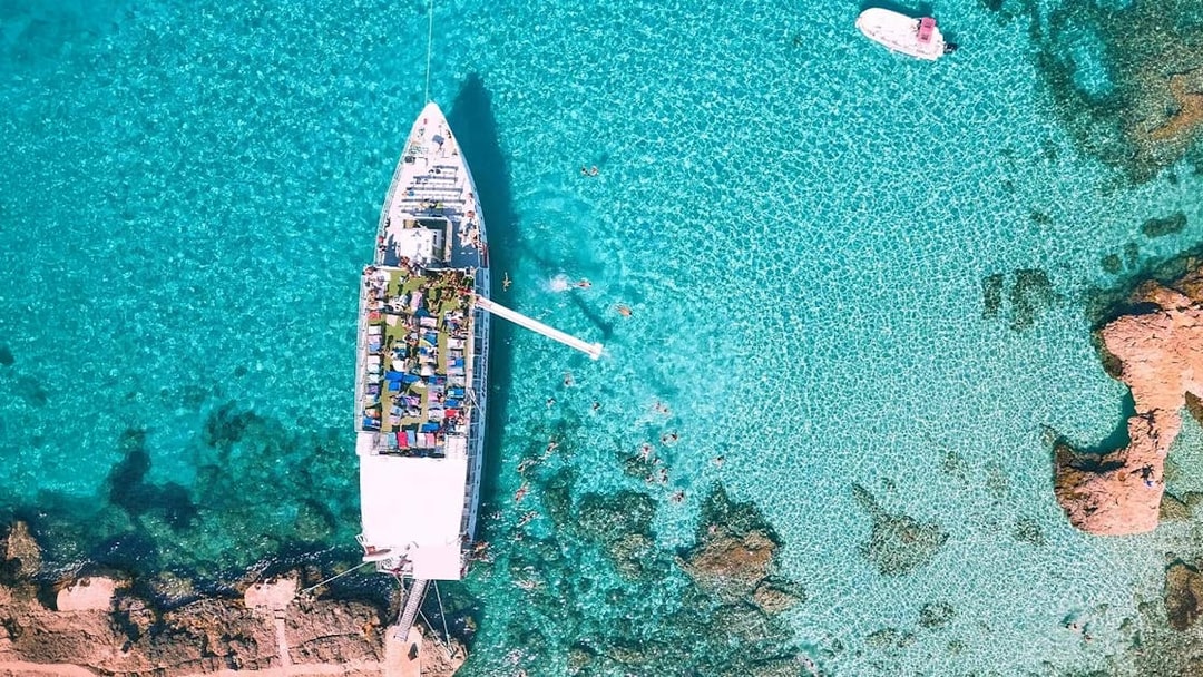 Cruise ship docked at Blue Lagoon, Malta, surrounded by clear turquoise water.
