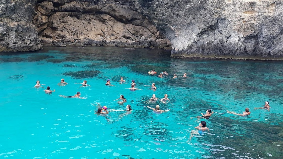 People swimming in the clear blue waters of the Blue Lagoon, Malta.