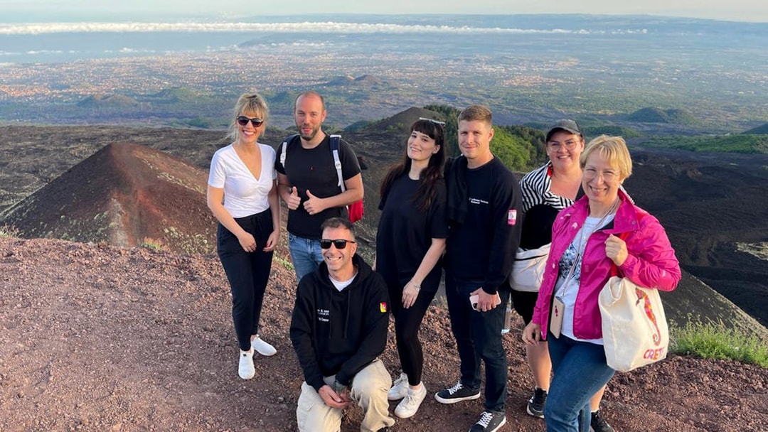 Tourists enjoying sunset views at Mount Etna summit.