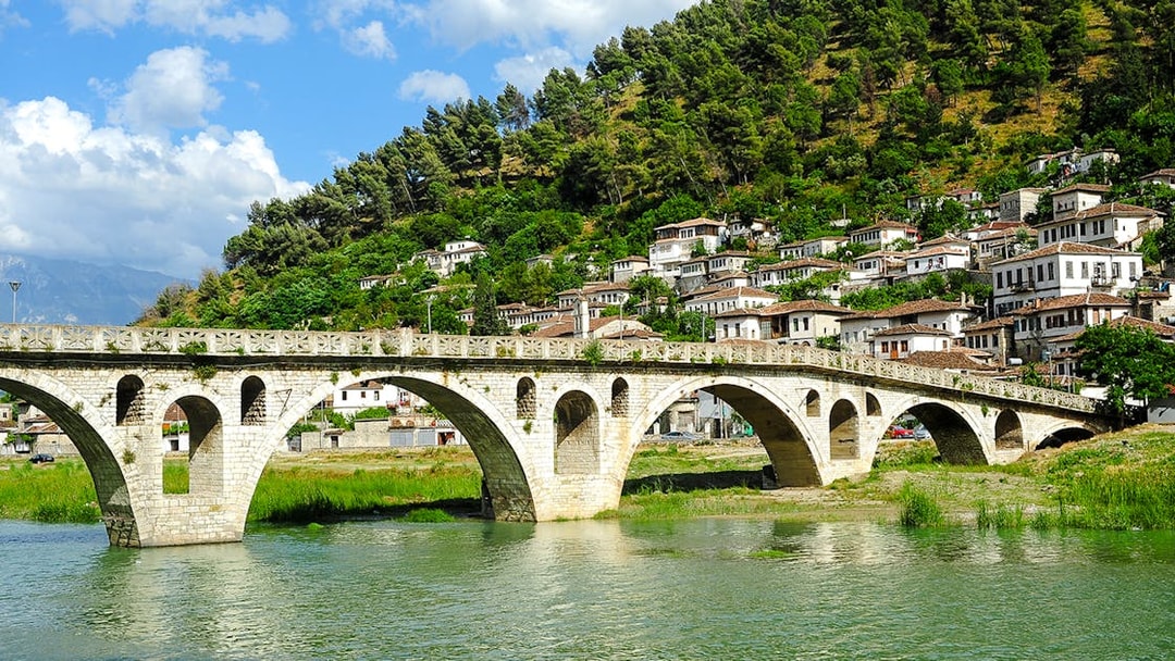 Gorica Bridge spanning river with hillside houses in Berat, Albania.