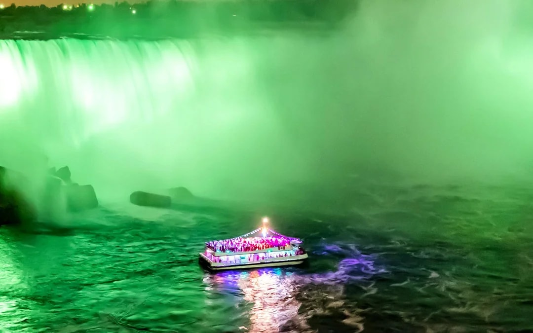 Boat illuminated at night near Niagara Falls during evening tour from Toronto.