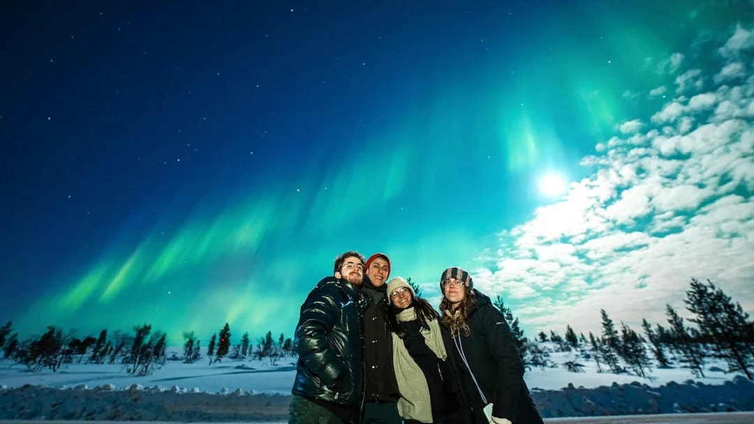 Northern Lights over snowy landscape with group on Tromso tour.