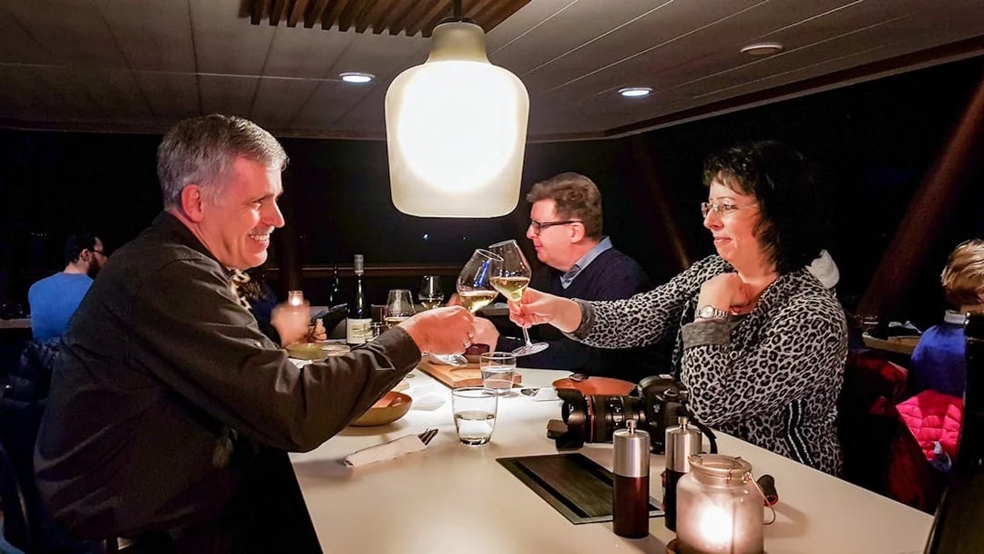 Guests toasting with wine glasses on an Aurora Boreal dinner cruise.