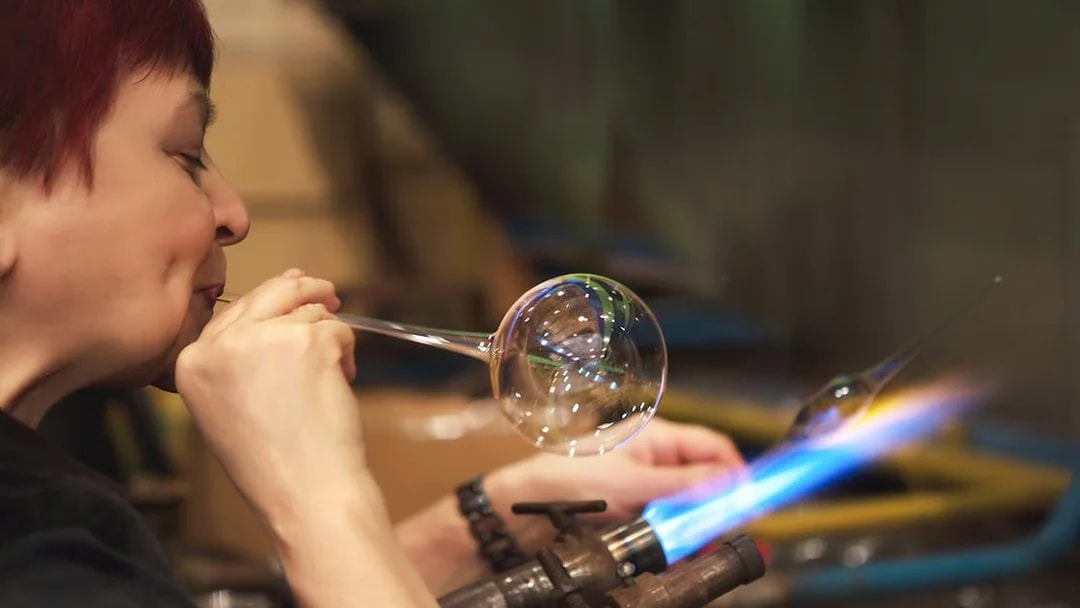 Glassblower shaping glass at Murano factory demonstration.