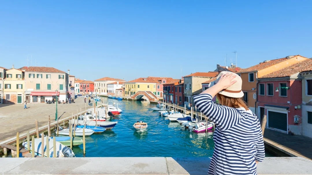 Traveler viewing colorful buildings and canal on Murano Island, near Venice, Italy.