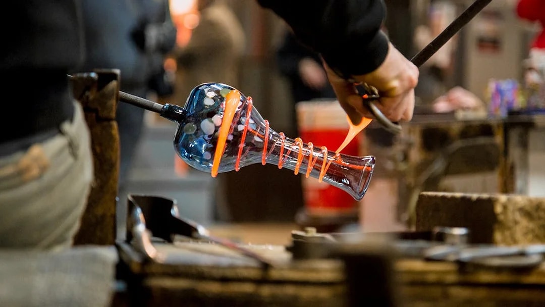 Artisan crafting glass vase in Murano workshop.