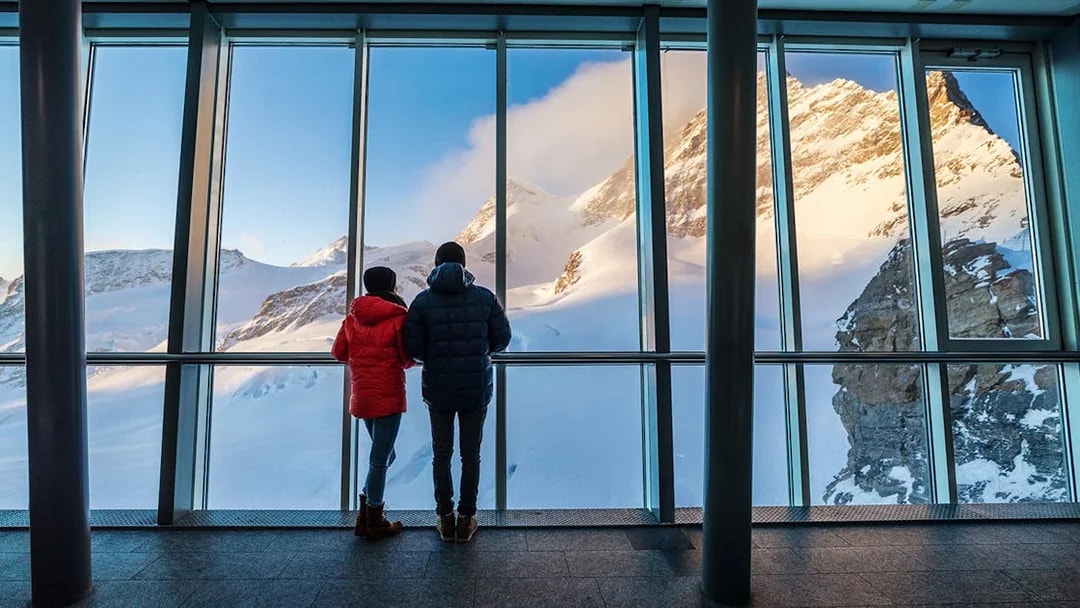 Visitors viewing snowy peaks from Jungfraujoch observatory, Switzerland.