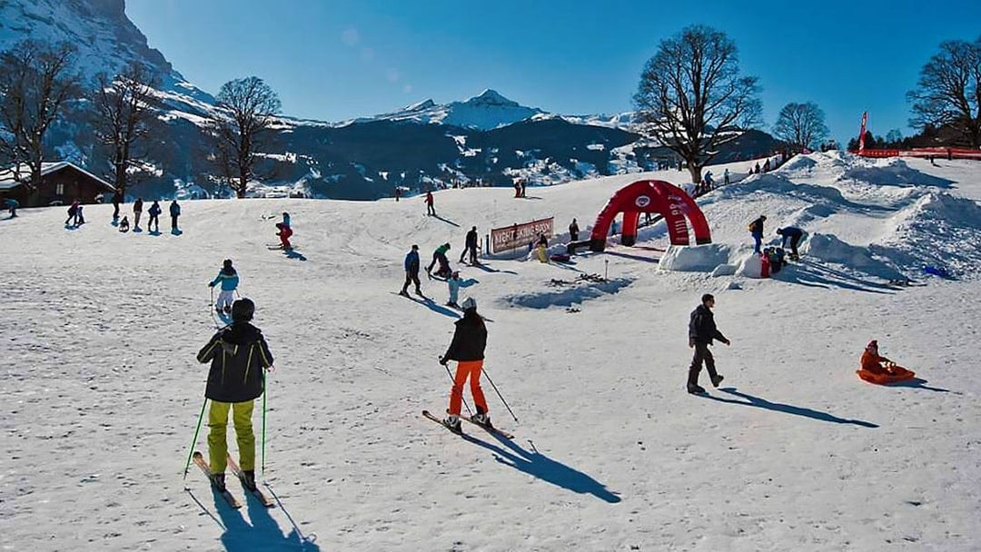 Skiers enjoying slopes in Jungfrau Region, Switzerland, with snowy mountains in the background.