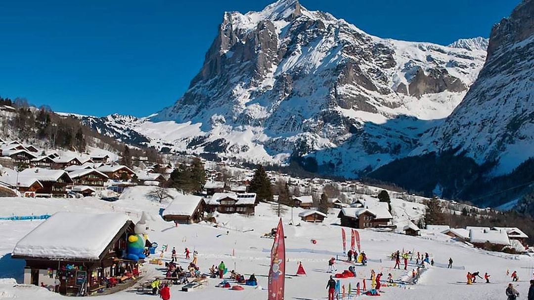 Skiers enjoying slopes in Jungfrau Region, Swiss Alps, with snowy mountain backdrop.