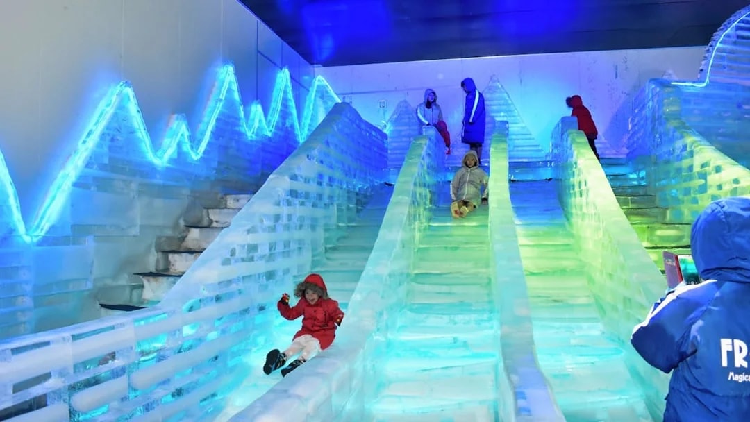 Children sliding down ice slides at Frost Magical Ice of Siam.
