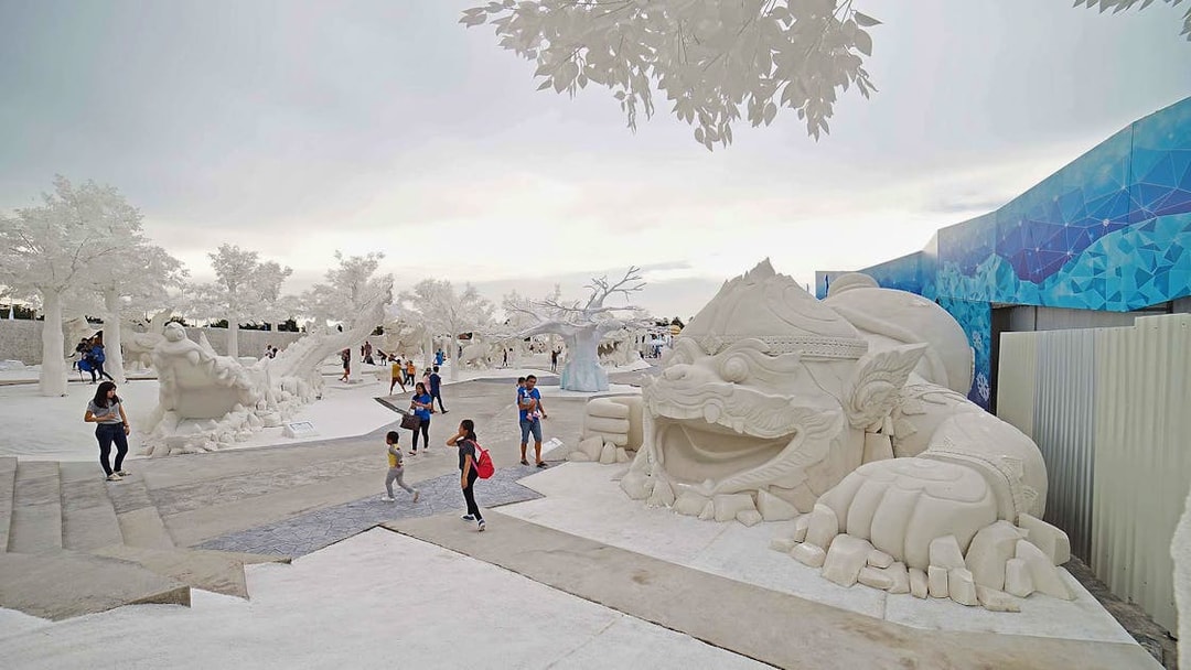 Visitors exploring Frost Magical Ice of Siam with large white sculptures in Pattaya, Thailand.