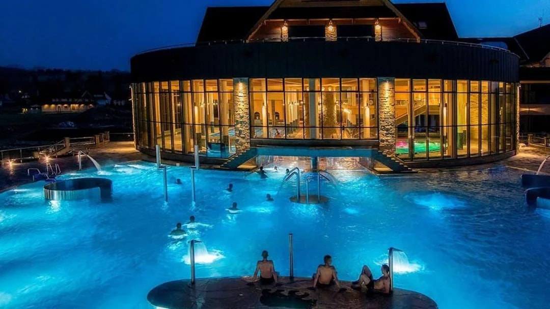 Chocholow Thermal Baths at night with illuminated pools and people relaxing.