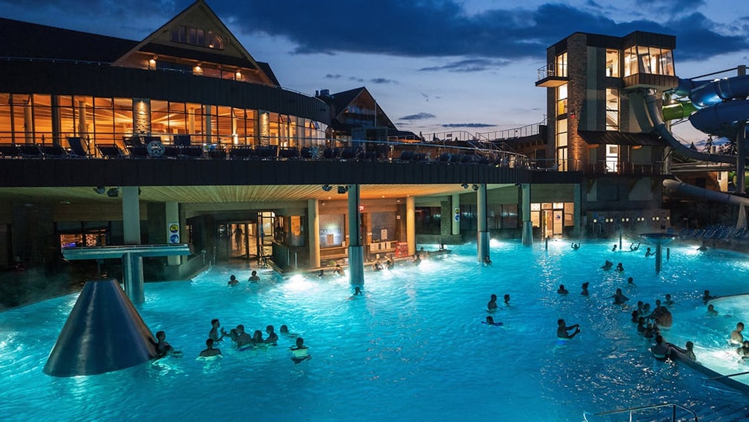 Chocholow Thermal Baths at night with visitors enjoying the illuminated pools.
