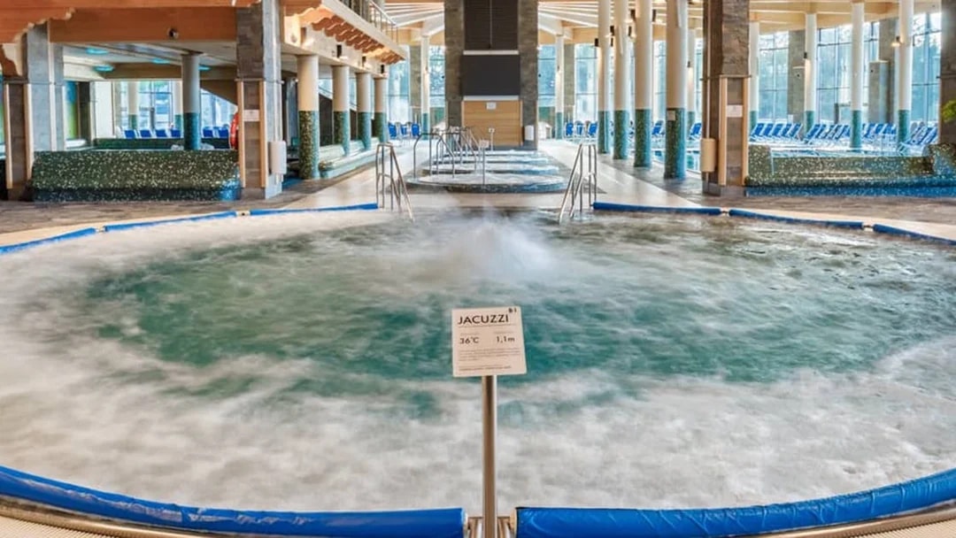 Indoor jacuzzi at Chocholow Thermal Baths with seating area and large windows.