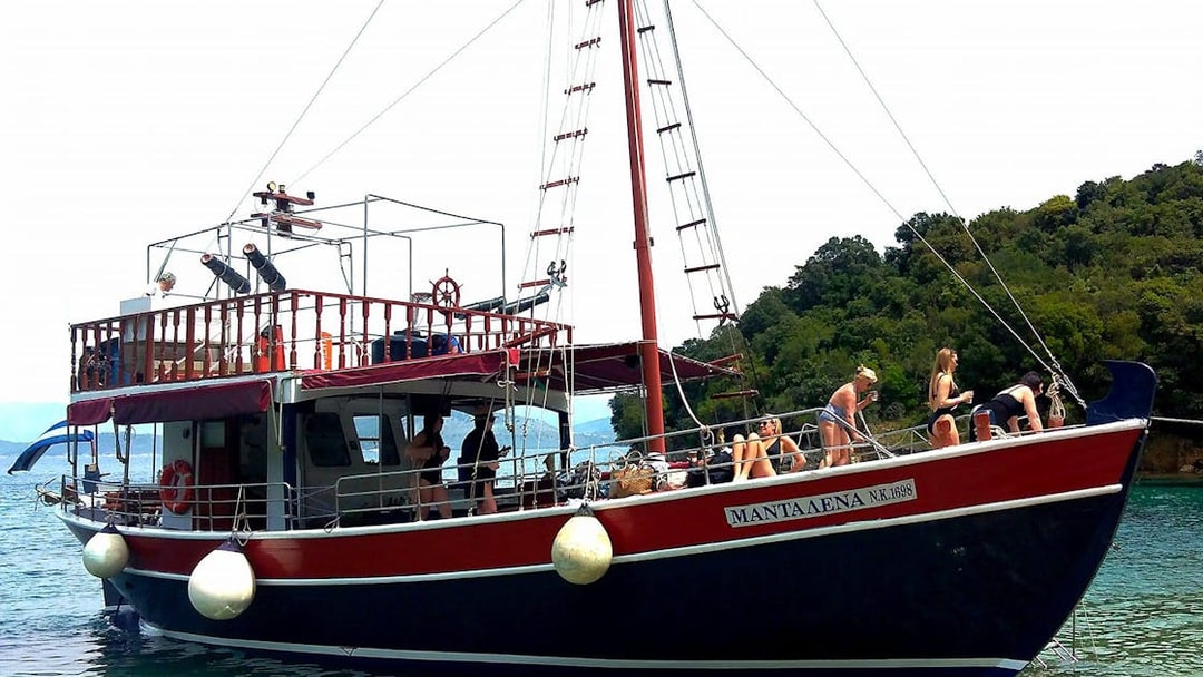 Boat with tourists enjoying a full-day trip in Corfu, Greece, near lush coastline.