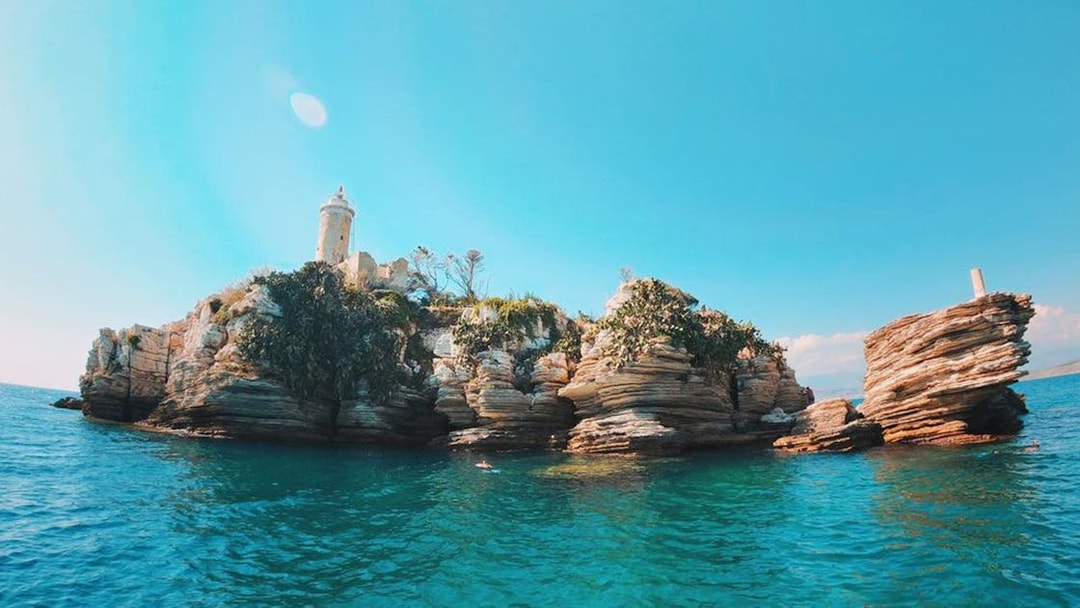 Rocky islet with lighthouse on Corfu boat trip route.
