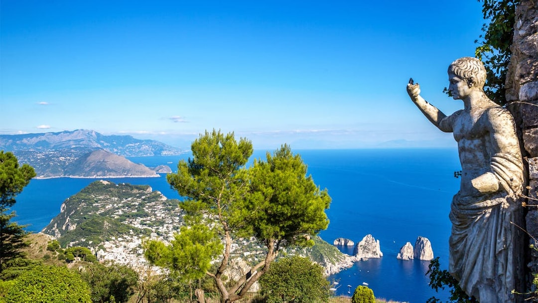 Capri island view with Faraglioni rocks and statue from Naples port tour.