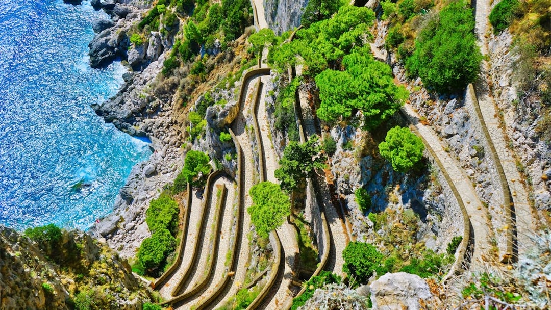 Winding path along rocky cliffs and greenery on Capri, Italy, seen from above.