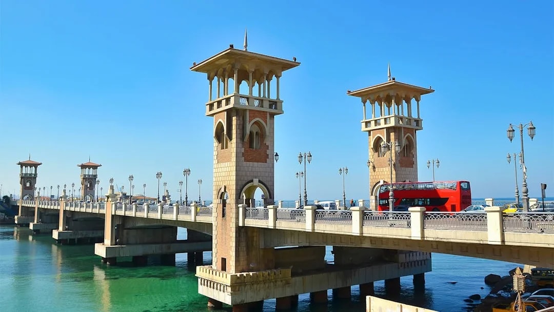 Stanley Bridge in Alexandria with a red double-decker bus crossing over the Mediterranean Sea.