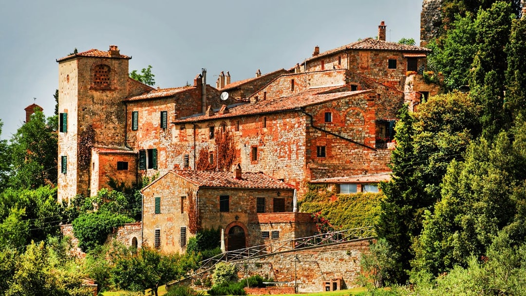 Historic stone buildings in Val D’Orcia, Tuscany, surrounded by lush greenery.