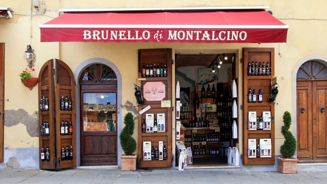 Wine shop entrance in Montalcino, Italy, featuring Brunello bottles on display.