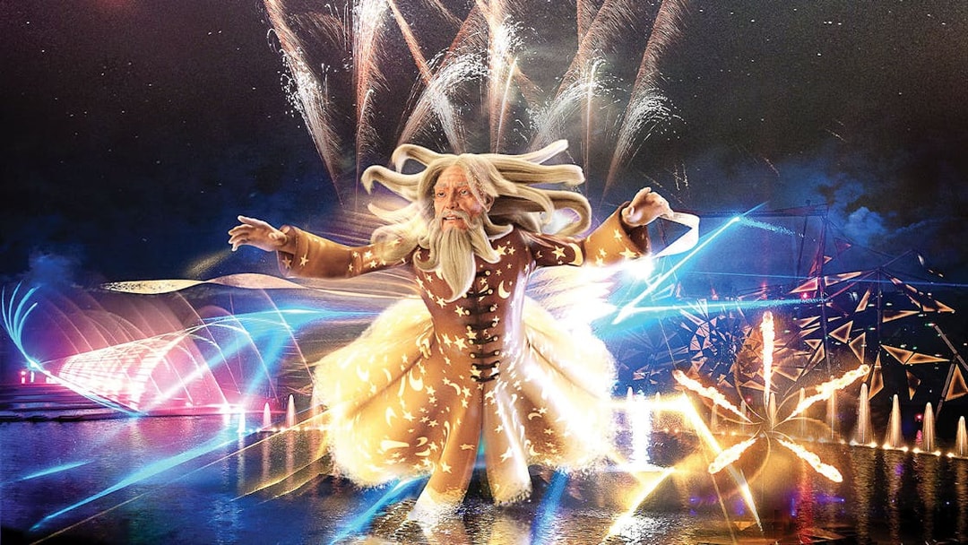 Futuroscope night show with illuminated wizard figure and fireworks display.