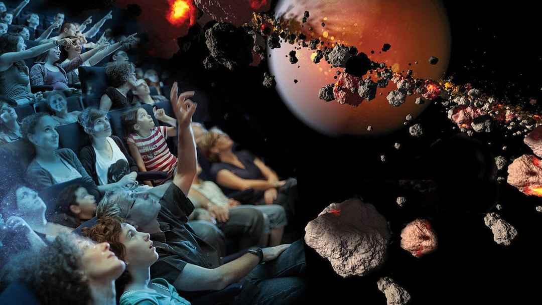 Visitors watching a space-themed show at Futuroscope, featuring asteroids and a planet.