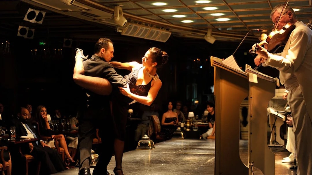 Dancers performing at Gala Tango Show with live violinist in Buenos Aires.